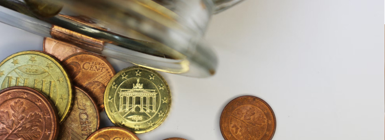 Geldmünzen fallen aus einem Glas