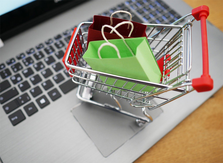 Gutscheine für Online-Supermärkte nutzen Einkaufswagen und Laptop
