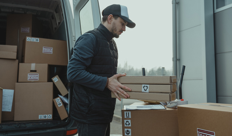 Paketbote mit Kartons Ein Paketbote räumt Päkchen aus dem Transporter