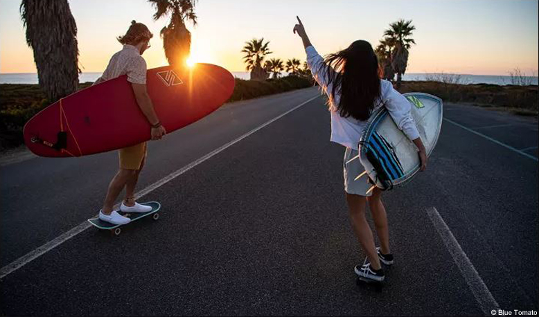 Mit Blue Tomato immer sportlich unterwegs 2 Personen mit Surfboard unter dem Arm beim Skaten